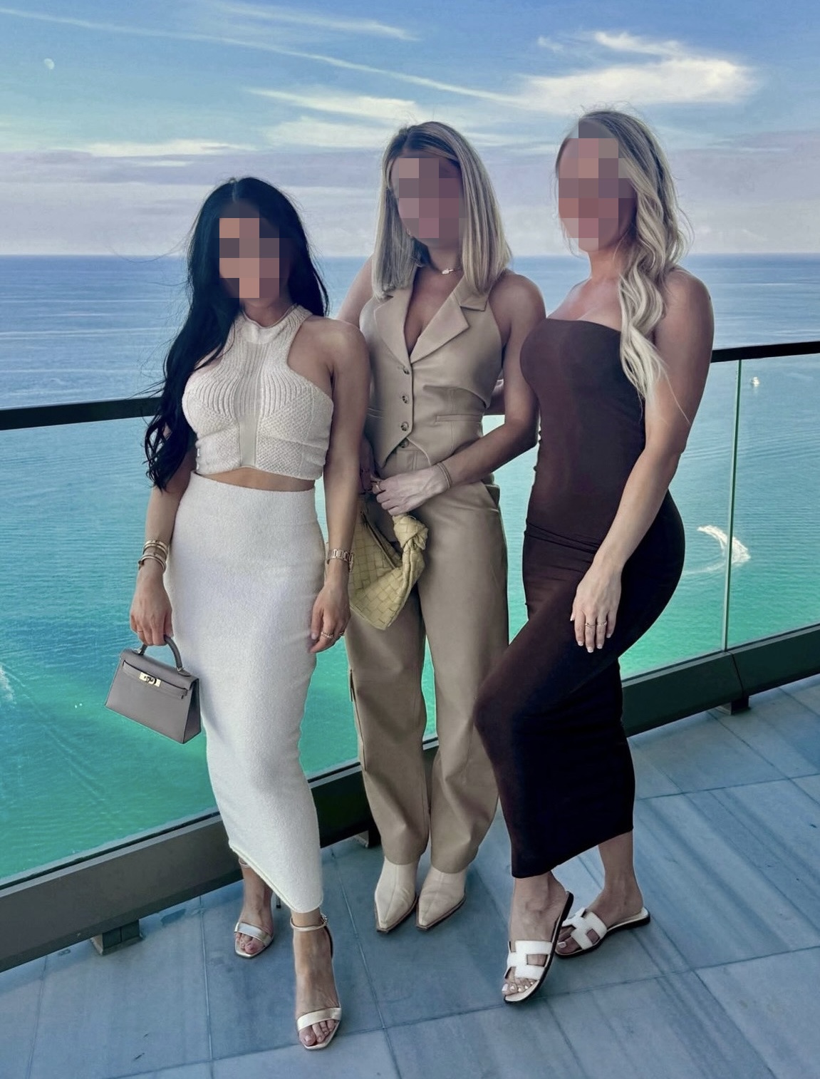 Three women posing on a balcony with an ocean view